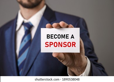 Become A Sponsor. Investment, Business Concept. Businessman Holding A Card With A Message Text Written On It