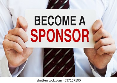 Become A Sponsor. Investment, Business Concept. Businessman Holding A Card With A Message Text Written On It