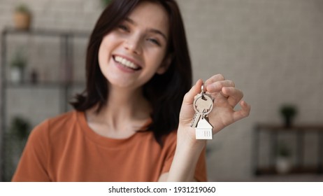Becoming homeowner. Cropped portrait of happy laughing millennial woman looking at camera showing key from new house rented leased purchased apartment. Focus on female owner hand holding bunch of keys
