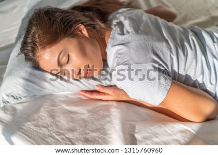 Bed Asian girl sleeping on stomach sleeper resting head on foam pillow.