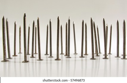 Bed of carpentry nails standing upright on a white reflective background - Powered by Shutterstock