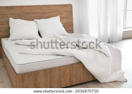 Bed with comfortable orthopedic mattress and bedding in room