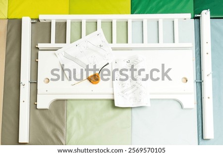 Bed components, tools, and an instruction manual are organized on padded mats, showing the initial steps of bed assembly.