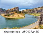 The bed of the deep river bends picturesquely into the hilly banks. Great Missouri River. Asphalt highway runs along the river. Cloudy autumn day. Trip to America