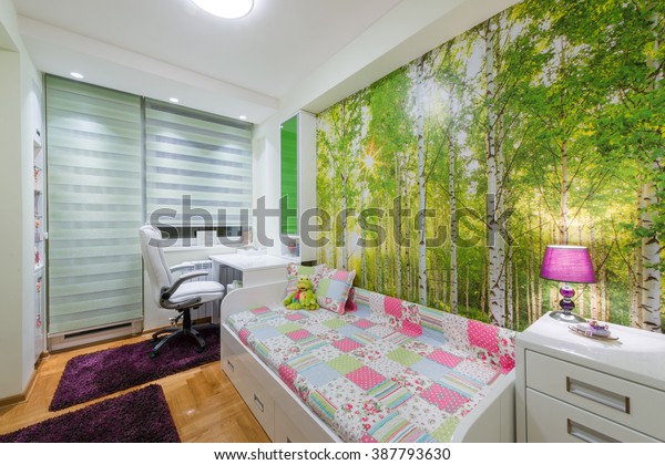 Bed and a desk in the children's room and a forest, nature wallpaper. 