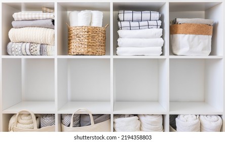 Bed linens closet neatly arrangement on shelves with copy space domestic textile Nordic minimalism comfortable storage. Rolled towels in straw basket duvet cover sheet pillow plaid in cupboard