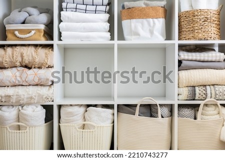 Bed linens closet neatly arrangement on shelves with copy space domestic textile Nordic minimalism comfortable storage. Rolled towels in straw basket duvet cover sheet pillow plaid in cupboard
