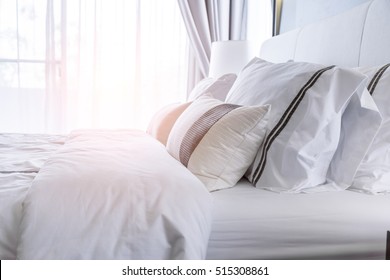 Bed maid-up with clean white pillows and bed sheets in beauty room. Close-up. Lens flair in sunlight. - Shutterstock ID 515308861
