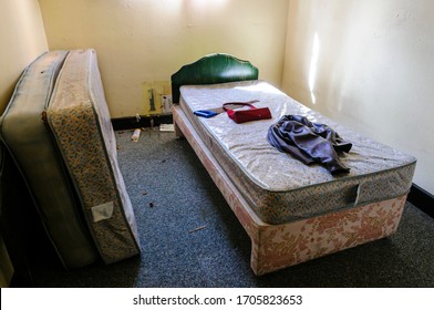 Bed In A Messy, Dirty Bedroom In An Abandoned Hotel Hostel With No Sheets Or Blankets.