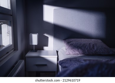 Bed at night in dark bedroom. Blue light and moonlight from window. Pillow, sheet and duvet ready for sleeping. Bedside table and nightstand. Scandinavian home interior design. Scary shade and shadow. - Shutterstock ID 2129610719