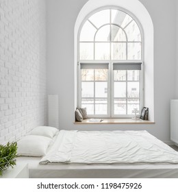 Bed from pallets in loft bedroom with white brick wall and big arch window