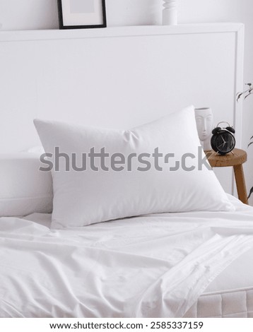 The bed with pillow and white sheets, elegantly draped over a mattress in the interior of a modern bedroom. One corner of the mattress is visible. Close-up photo. Suitable for mockup