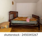 A bed with a pink towel on it and a wooden headboard. The room is empty and has a simple, minimalistic feel