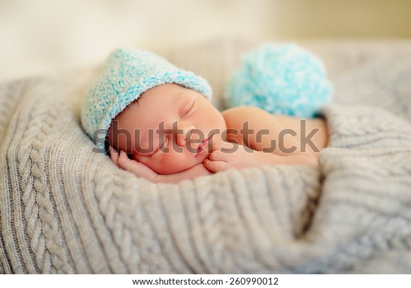 in bed\
sleeping baby in a blue cap with a large\
bubo