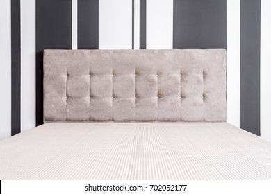 Bed With Tufted Velour Headboard Next To Black And White Striped Wallpaper