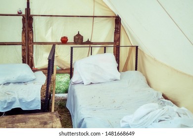 Bed Under A Large Tent Retro Field Hospital. Military Field Medicine In The 18th Or 19th Century. Portable Hospital For Wounded Soldiers.