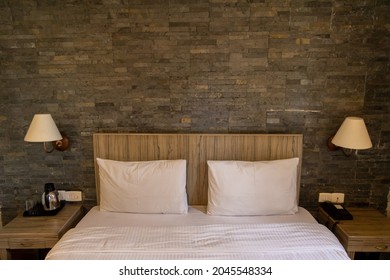 A Bed With White Bedsheet And Pillow Covers And Bed Side Lamps Fitted On The Wall
