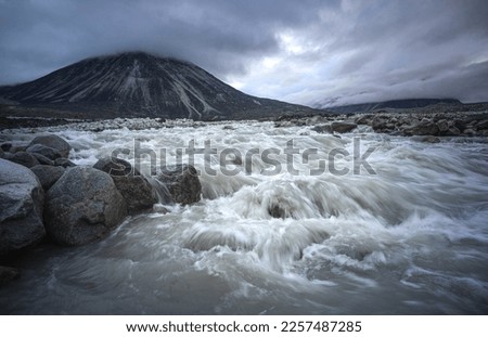 Bed of wild Weasel river in remote arctic valley on a cloudy and rainy day. Dramatic arctic landscape of Akshayuk Pass, Baffin Island, Canada