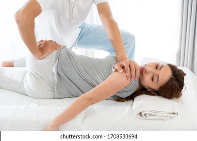 In bed, a woman is pelvic corrected by a man.