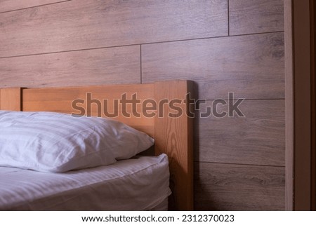 The bed is wooden. Bed linen and pillow. On the background of a wooden wall.