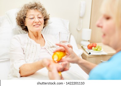 A Bedridden Senior Woman Receives An Oral Medication From Nursing Assistant