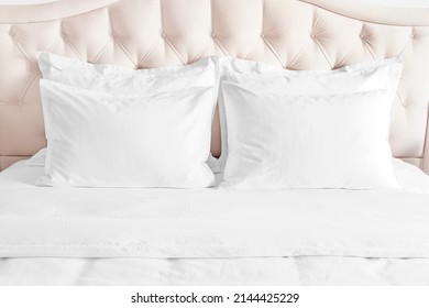 Bedroom with bed and white bedding White pillows, duvet and duvet case on bed with beige headboard.  Bed with clean white pillows and bed sheets in beautiful bedroom.