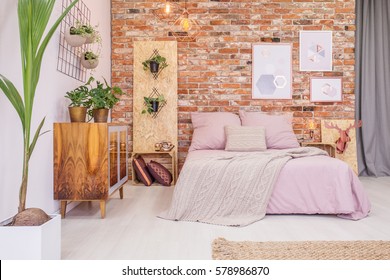 Bedroom With Double Bed, Brick Wall And Green Decorative Plants