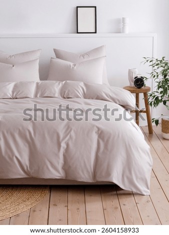 Bedroom with a double bed, fluffy down comforter with a beige duvet cover, four pillows, one beige cushion and wooden bedside table with vase. Close-up front view vertical photo. Suitable for mockup