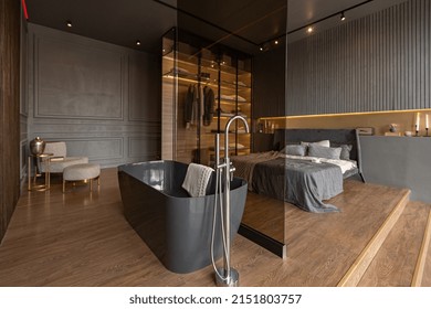bedroom and freestanding bath behind a glass partition in a chic expensive interior of a luxury home with a dark modern design with wood trim and led light - Shutterstock ID 2151803757