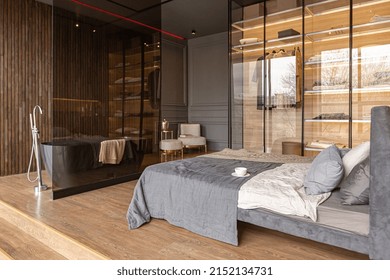 Bedroom And Freestanding Bath Behind A Glass Partition In A Chic Expensive Interior Of A Luxury Home With A Dark Modern Design With Wood Trim And Led Light