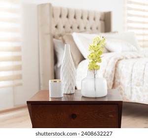 Bedroom Harmony: Close-Up of a Wooden Nightstand Featuring Elegant Decorative Vases and Fresh Greenery, Complementing the Soft Tones of a Plush Tufted Headboard in a Well-Appointed Room, natural light - Powered by Shutterstock