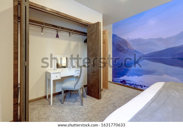 Bedroom interior with bright purple wallpaper murals of mountains, beige carpet and white make up desk. Small, cozy and luxury.