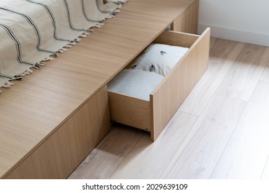 Zimmereinrichtung, Holzbett im modernen Zimmer. Möbel-Design mit offener Holzschublade, weißes Kissendekor in Schachtel. Braun bequeme Aufbewahrung für Bettkissen.