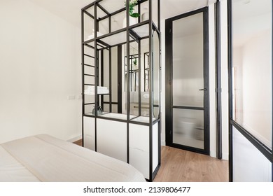 Bedroom With King Size Bed And Black Metal Shelf With Sink And Separate Toilet With Opaque Glass Door