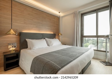 Bedroom With Large Double Bed, Good View From The Window, Dark Wood Tables With Flowers, Chrome Night Coat And Light Wooden Floors