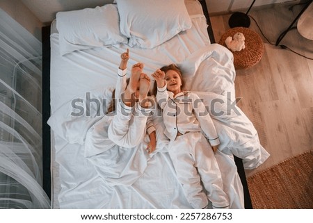 Similar – Mother reading book to her sons in the bed