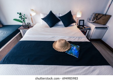 A bedroom with mordern style contemporary with black runner sheet. Bright light from the white curtain in the morning.Full with amenities hat bag and fridge.