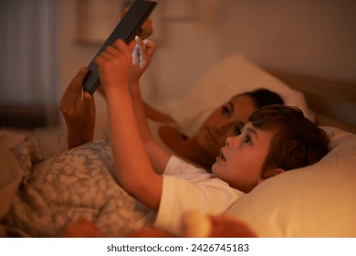 Bedroom, mother and son with tablet, night and family with ebook and connection with social media. Mama, home and boy with technology or bedtime story with lights or bonding together with digital app - Powered by Shutterstock