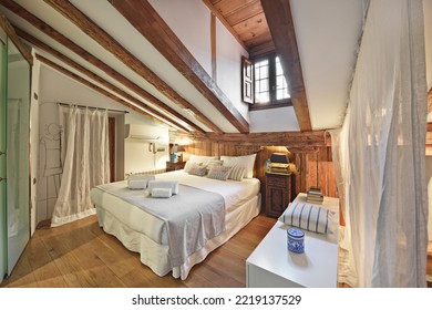 Bedroom of an old house located in the attic with sloping ceilings with oak floors and exposed wooden beams
