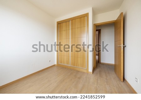 bedroom with two-section built-in wardrobe with large oak sliding doors and wooden floor and access door of the same material Foto d'archivio © 