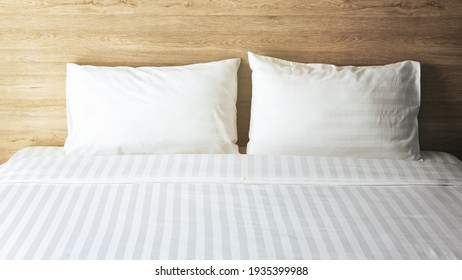 Bedroom with white bed, White two pillows, White duvet on the bed with wooden headboard and sunlight