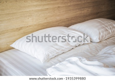 Bedroom with white bed, White two pillows, White duvet on the bed with wooden headboard and sunlight