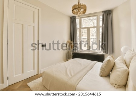 a bedroom with white walls and wood flooring the room has a large bed, a chandel, two bedside lamps and a