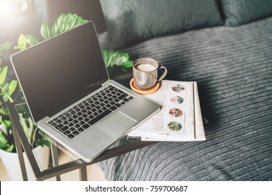 Bedroom, Workplace Without People, Close-up Of Laptop With Blank Screen On Glasses Table, Desktop. Space For Text, Logo, Advertising.Nearby Is Newspaper, Cup Of Coffee.Mock Up.Nobody.