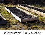 Beds for growing vegetables, made of rough boards and filled with fresh earth. Preparation of garden for planting plants. Gardening on swampy soils.