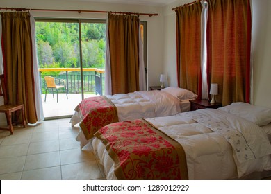 Beds In A Hotel Room. White Feather Blankets. Red Curtains. Two Beds. One Double Bed. View From The Window To The Mountains