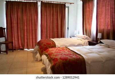 Beds In A Hotel Room. White Feather Blankets. Red Curtains. Two Beds. One Double Bed. View From The Window To The Mountains