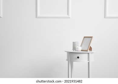 Bedside Table With Photo Frame And Candles Near White Wall