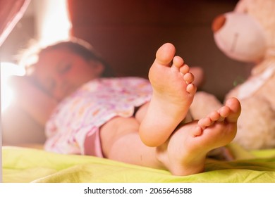 Bedtime Concept. Funny Portrait Of Sleepy Cute Child Girl In The Bed. Selective Focus On Groomed Bare Feet. 