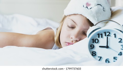 Bedtime. Little Girl Goes To Sleep Early Evening With Alarm Clock On 9 P.m., Wearing White Cat, Bunny Sleep Mask. Soft Bed With White Linen.Child Sleep Regime Hours,daily Routine.Sweet Dreams Concept.